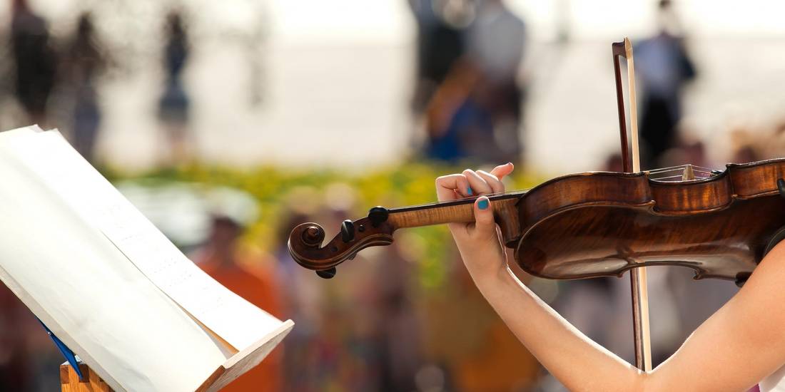Eine Violine in der Hand eines Menschen mit lackierten Fingernägeln © Adobe Stock