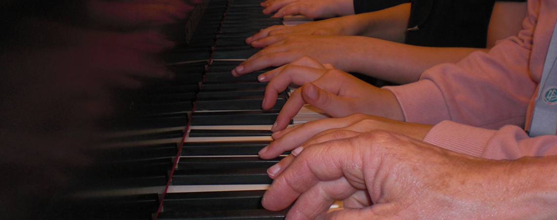junge und alte Hände spielen auf der Klaviertastatur